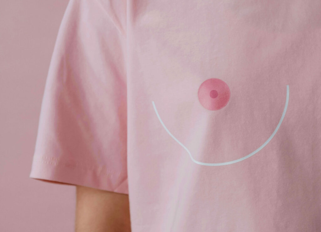 Brustbereich einer Person im pinken T-Shirt mit stilisierter Brustdarstellung.