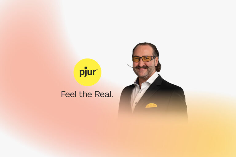Alexander Giebel, Gründer und CEO von pjur, neben dem gelben pjur-Logo mit dem Slogan „Feel the Real“.