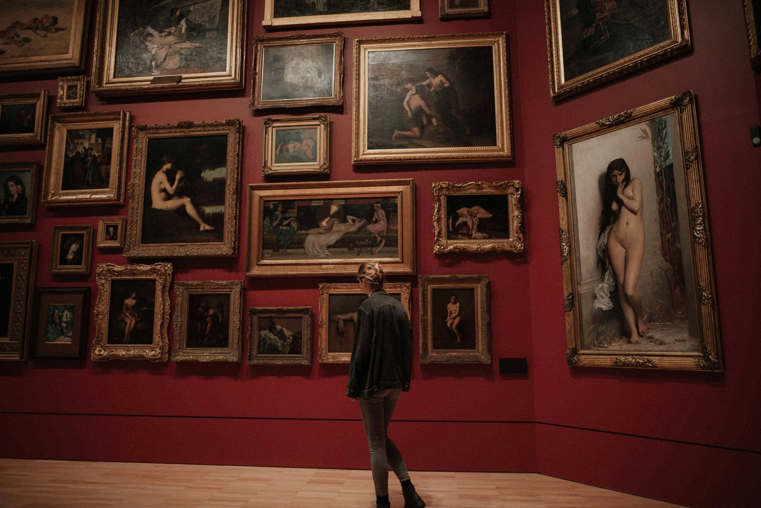 Frau in Kunstgalerie/ Museum vor einer Wand mit Gemälden